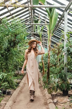 A beautiful young woman takes care of plants in a greenhouse. The concept of gardening and an eco-friendly lifestyle