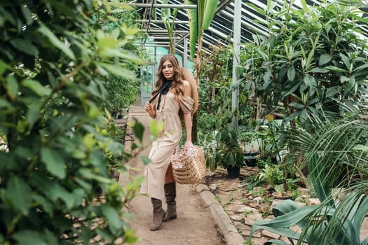 A beautiful young woman takes care of plants in a greenhouse. The concept of gardening and an eco-friendly lifestyle