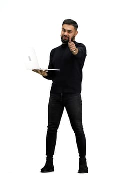 A man, in full height, on a white background, uses a laptop.