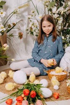 Two girls in a beautiful Easter photo zone with flowers, eggs, chickens and Easter bunnies. Happy Easter holiday