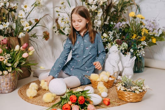 Two girls in a beautiful Easter photo zone with flowers, eggs, chickens and Easter bunnies. Happy Easter holiday