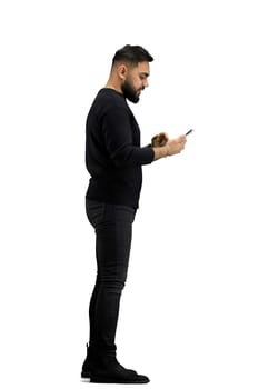 A man, full-length, on a white background, uses a phone.