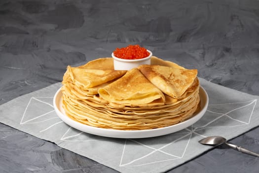 Pancakes with red caviar on grey background. Copy space...