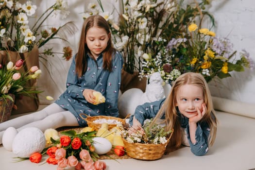 Two girls in a beautiful Easter photo zone with flowers, eggs, chickens and Easter bunnies. Happy Easter holiday