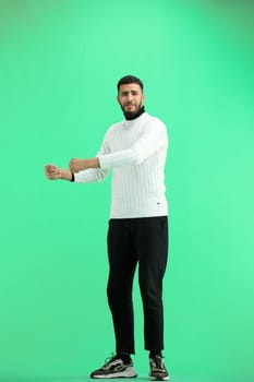 A man, full-length, on a green background, raised his hands up.