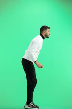 A man, full-length, on a green background.