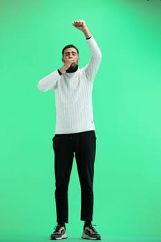 A man, full-length, on a green background, rejoices.