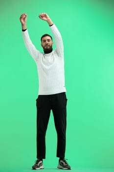 A man, full-length, on a green background, waving his arms.
