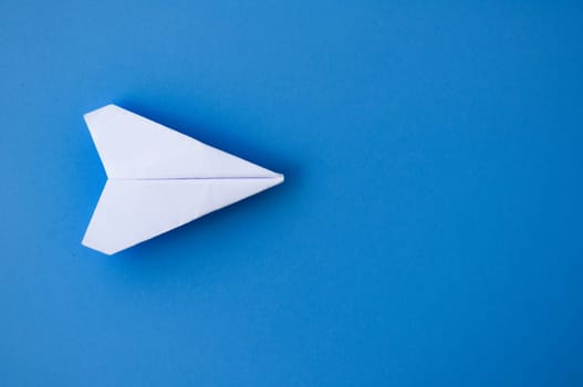 Top view of a white paper airplanes origami flying on blue background.