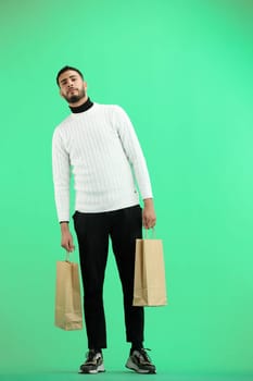 A man, full-length, on a green background, with bags.