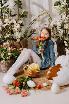 Two girls in a beautiful Easter photo zone with flowers, eggs, chickens and Easter bunnies. Happy Easter holiday