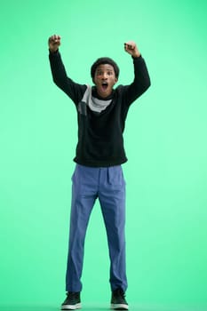 A man, full-length, on a green background, raised his hands up.