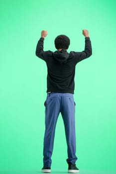 A man, full-length, on a green background, raised his hands up.