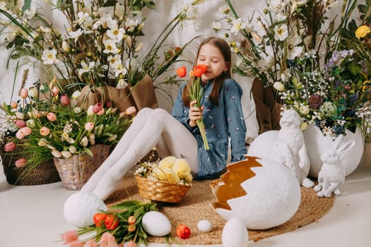 Two girls in a beautiful Easter photo zone with flowers, eggs, chickens and Easter bunnies. Happy Easter holiday