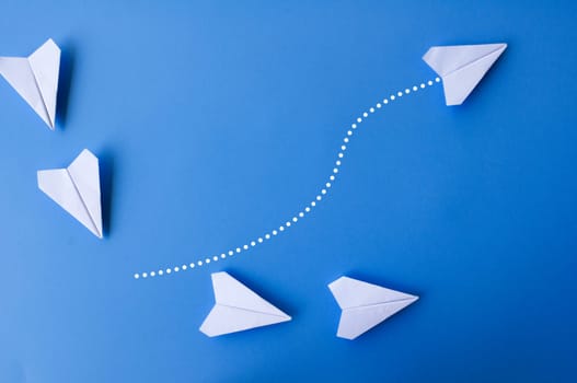 Top view of white paper airplanes with one flying at different direction