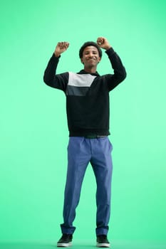 A man, full-length, on a green background, dancing.