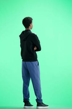 A man, full-length, on a green background, crossed his arms.