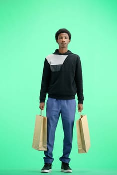 A man, full-length, on a green background, with bags.