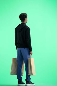 A man, full-length, on a green background, with bags.