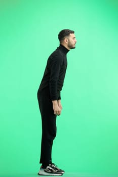 A man, full-length, on a green background.