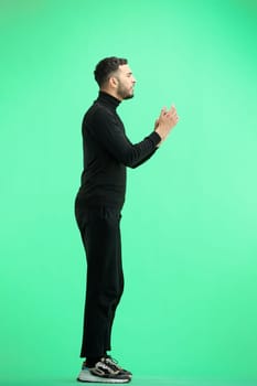 A man, full-length, on a green background, claps.