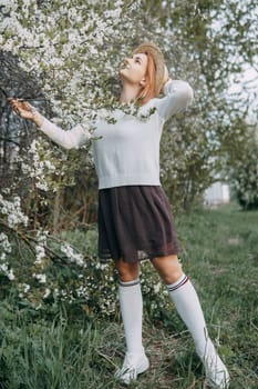 Portrait of a woman in a straw hat in a cherry blossom. Free outdoor recreation, spring blooming garden