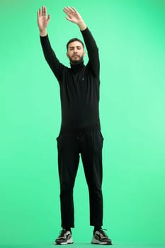 A man, full-length, on a green background, waving his arms.