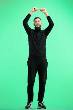 A man, full-length, on a green background, waving his arms.