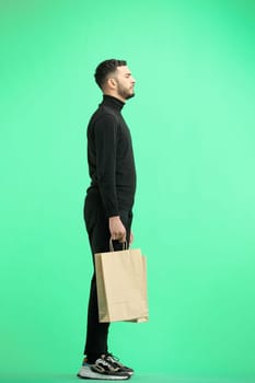 A man, full-length, on a green background, with bags.