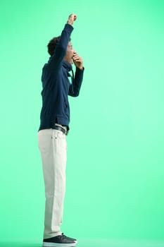 A man, full-length, on a green background, rejoices.