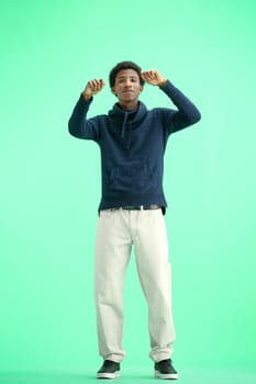 A man, full-length, on a green background, dancing.