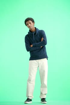 A man, full-length, on a green background, crossed his arms.