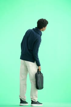 A man, full-length, on a green background, with a briefcase.
