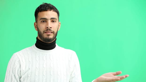 A man, close-up, on a green background, points to the side.