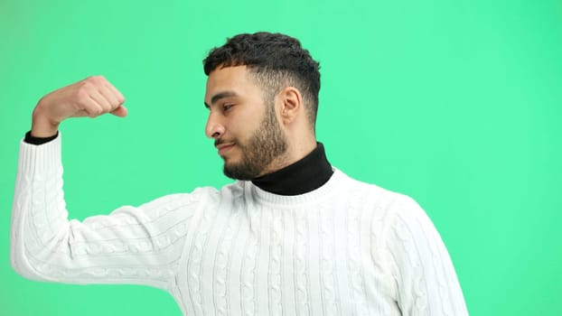 Man, close-up, on a green background, shows strength.