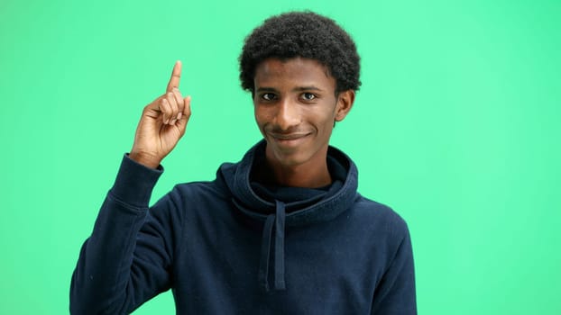 Man, close-up, on a green background, pointing up.