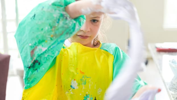 In a modern kitchen, a homeschooled girl is engrossed in creating homemade slime, a fun and educational hands-on project that enhances her creativity and problem-solving skills.