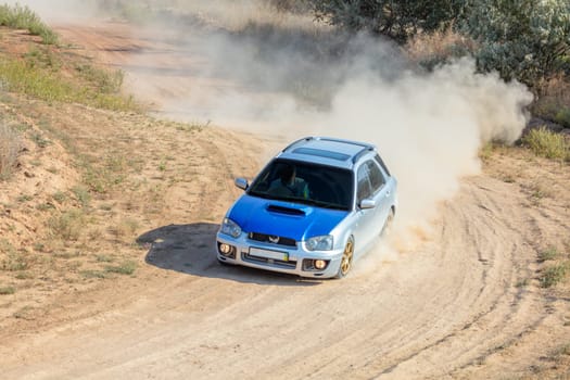 Sunny summer day. Dusty rally track. A rally car makes a lot of dust in a turn 15