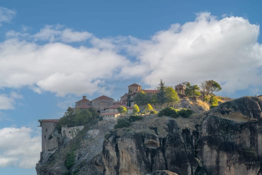 Greece. Sunny summer day in Kalambaka. Large rock monastery with red roofs above the clouds