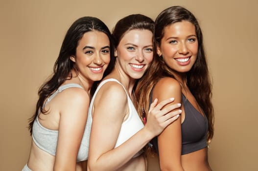 Happy young arabic, latin and european women in different underwear enjoy free time, natural beauty, isolated on beige background, studio. Lifestyle, health care, freshness