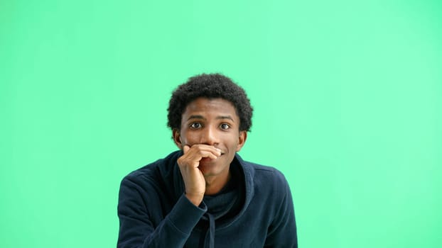 A man, close-up, on a green background, tells a secret.