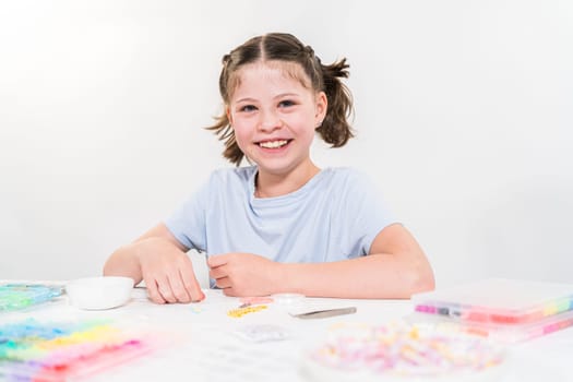 Little girl enjoys crafting colorful bracelets with vibrant clay beads set.