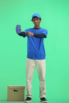 The deliveryman, in full height, on a green background, with a box, shows the phone.