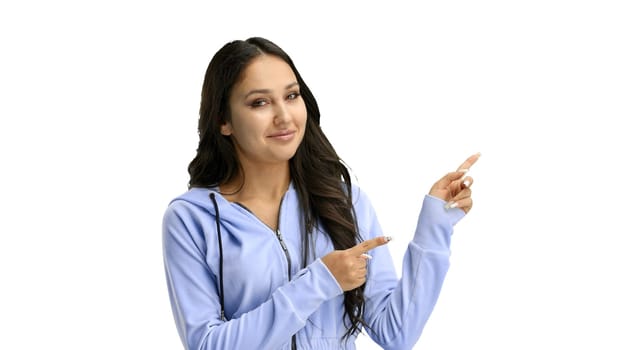 A woman, close-up, on a white background, points to the side.