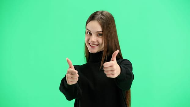 A woman, close-up, on a green background, shows her thumbs up.
