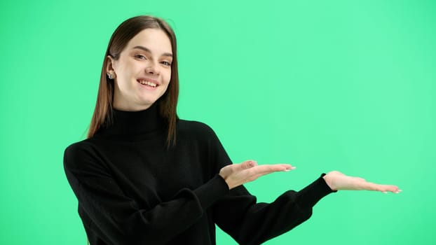 A woman, close-up, on a green background, points to the side.