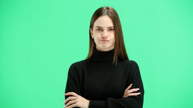 A woman, close-up, on a green background, crossed her arms.