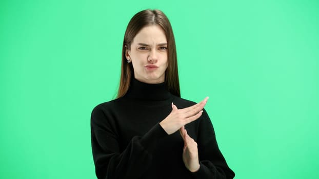 A woman, close-up, on a green background, shows a pause sign.