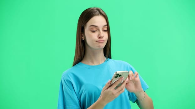 A woman, close-up, on a green background, shows a phone.