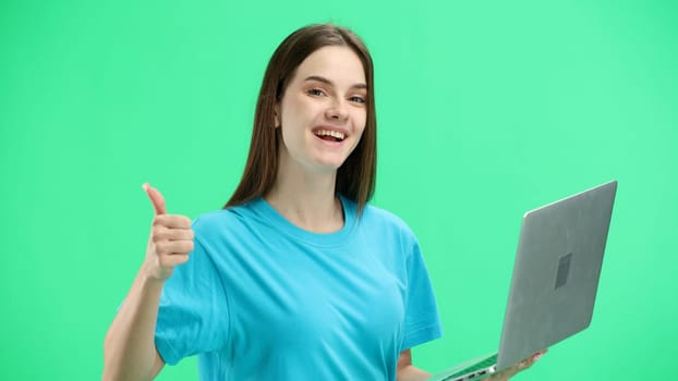 A woman, close-up, on a green background, uses a laptop.